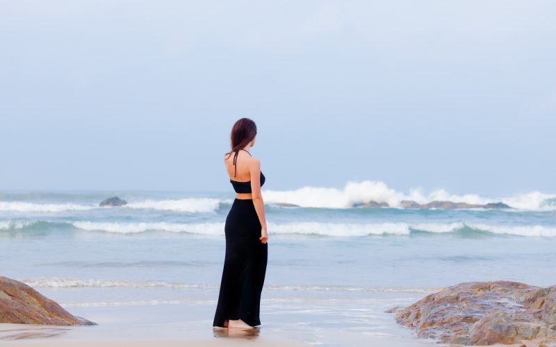 beautiful young woman standing on the sand coast in sunny Sri Lanka