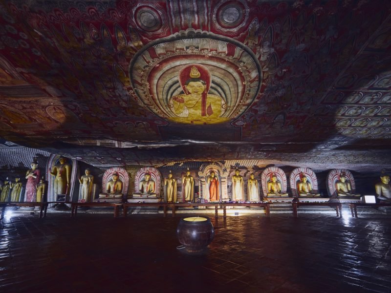 Statues and paintings inside of largest and best preserved cave temple complex in Sri Lanka